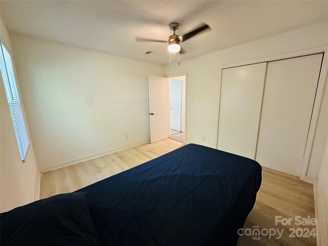 unfurnished bedroom featuring light hardwood / wood-style flooring, ceiling fan, and a closet