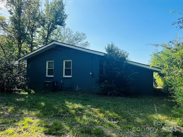 view of side of property with a yard and central air condition unit