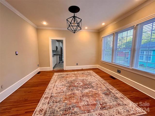 spare room with crown molding, a chandelier, and hardwood / wood-style floors