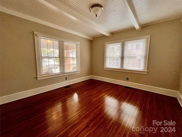 unfurnished room with beamed ceiling, a wealth of natural light, and hardwood / wood-style floors