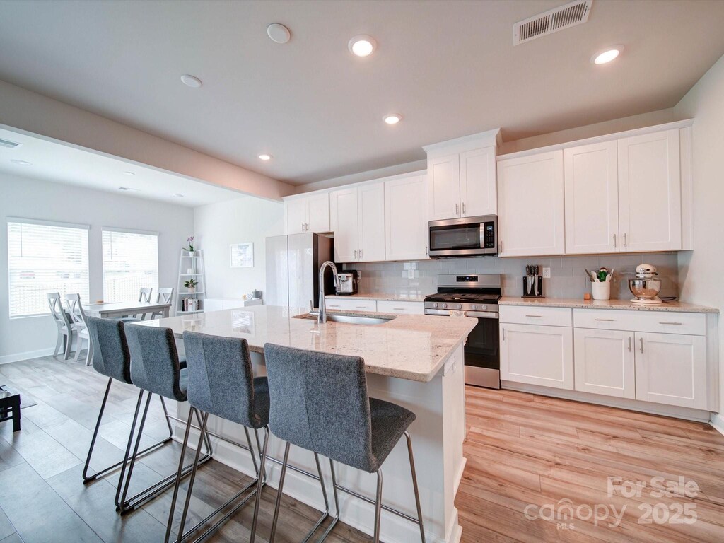 102 Guardian Gate Dr, Mooresville, NC 28115 - kitchen featuring visible vents, backsplash, a breakfast bar, stainless steel appliances, and a sink