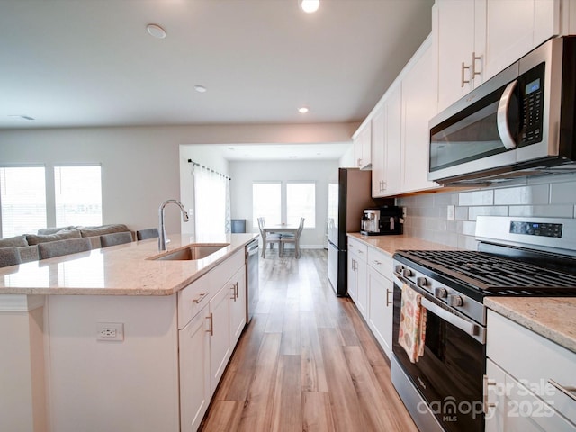 kitchen featuring sink, white cabinetry, a kitchen island with sink, and appliances with stainless steel finishes