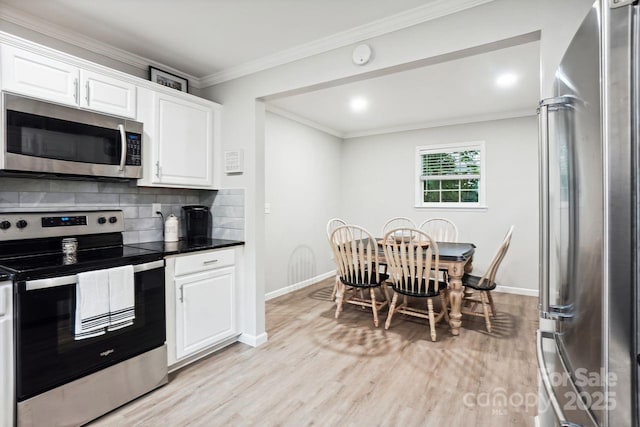 kitchen featuring tasteful backsplash, white cabinetry, stainless steel appliances, crown molding, and light wood-type flooring