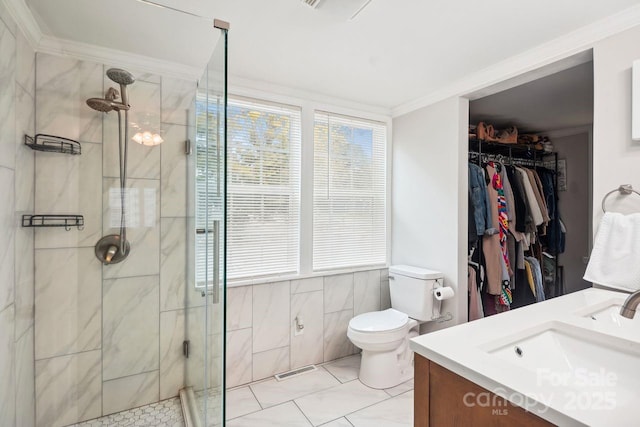 bathroom featuring crown molding, vanity, toilet, and a shower with door