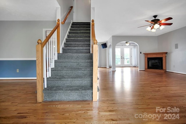 stairs with ceiling fan, hardwood / wood-style flooring, and french doors