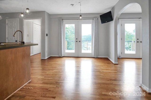 interior space with french doors, light hardwood / wood-style flooring, and hanging light fixtures