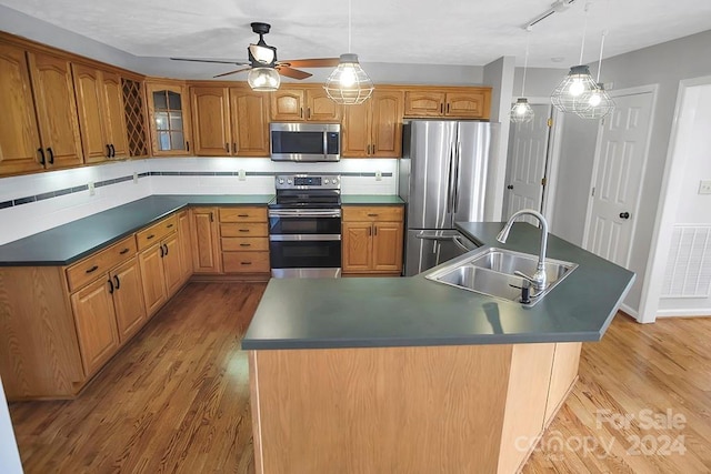 kitchen featuring light hardwood / wood-style floors, sink, stainless steel appliances, and decorative light fixtures