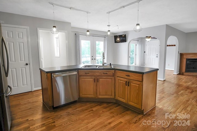 kitchen featuring dark hardwood / wood-style floors, sink, stainless steel appliances, a center island with sink, and decorative light fixtures