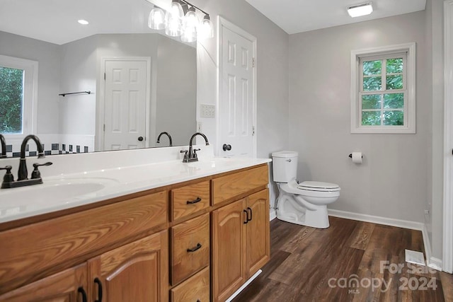 bathroom with a wealth of natural light, hardwood / wood-style floors, vanity, and toilet