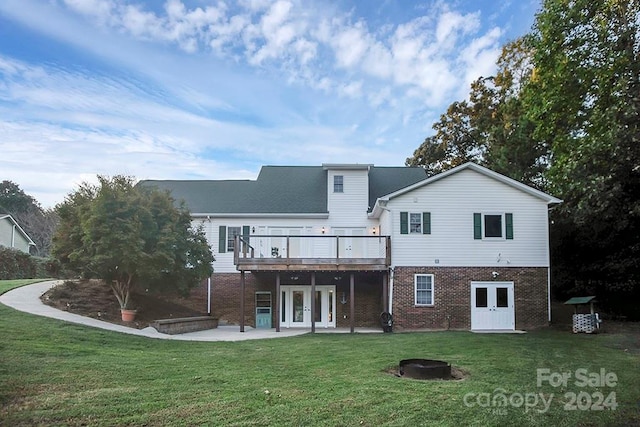 rear view of house featuring french doors, a fire pit, a lawn, and a patio