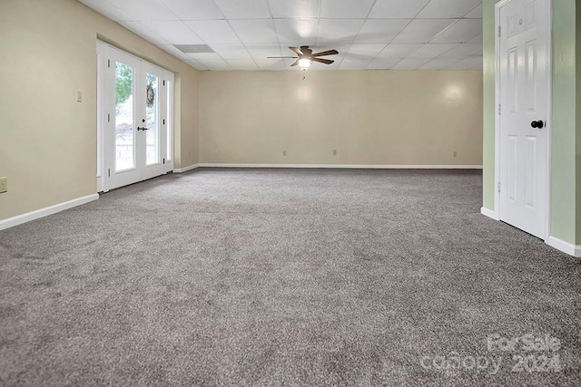 carpeted empty room with a paneled ceiling, ceiling fan, and french doors