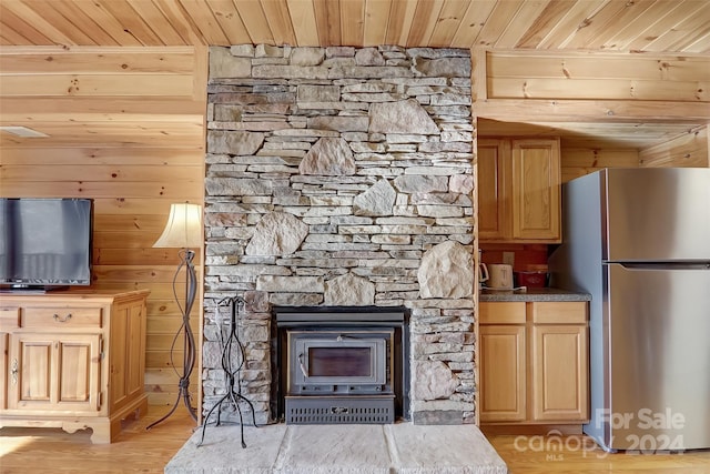 interior space with a wood stove, light hardwood / wood-style flooring, and wooden ceiling