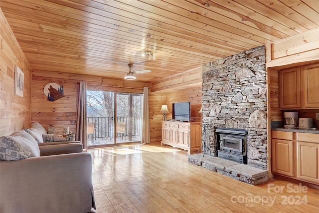 unfurnished living room featuring light hardwood / wood-style floors, a wood stove, wood ceiling, and wood walls