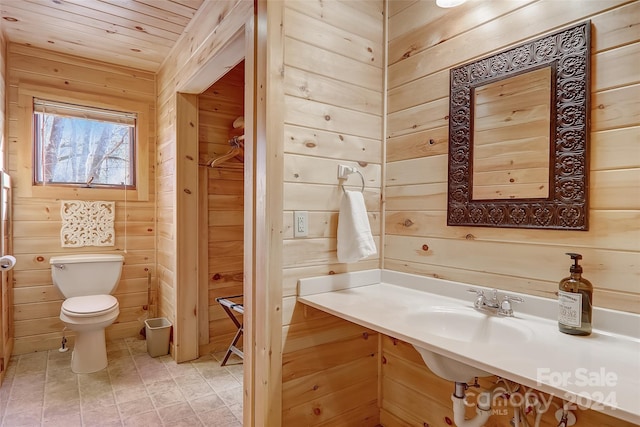 bathroom featuring wood walls, sink, wood ceiling, and toilet