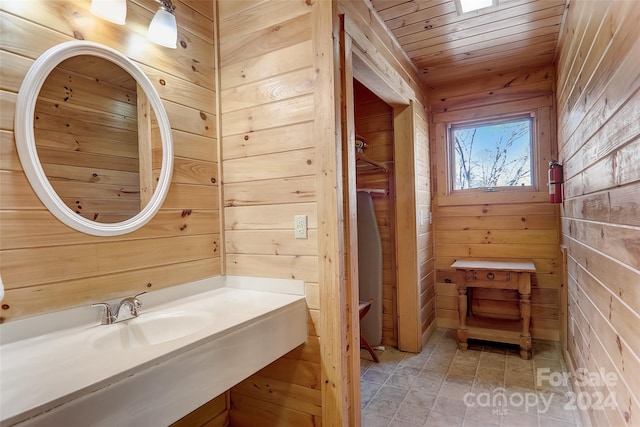 bathroom with wood ceiling, wood walls, and sink