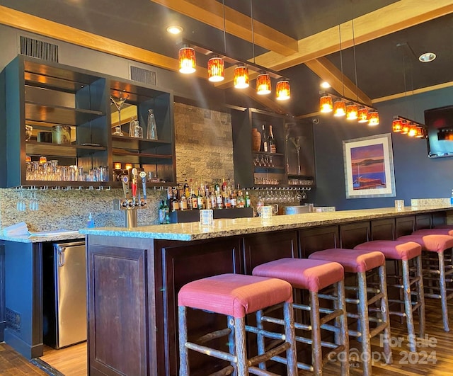 bar with light hardwood / wood-style flooring, beamed ceiling, decorative light fixtures, light stone counters, and dark brown cabinetry