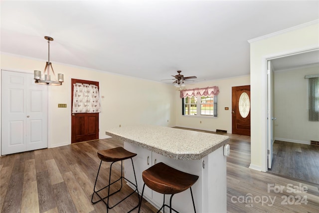 kitchen featuring ceiling fan with notable chandelier, decorative light fixtures, light hardwood / wood-style floors, and a kitchen breakfast bar