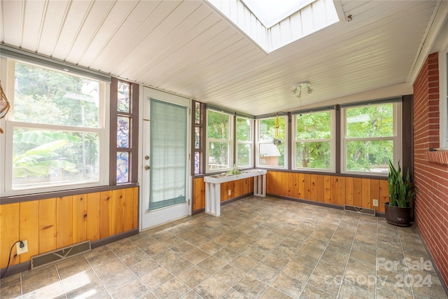 unfurnished sunroom featuring wood ceiling, a skylight, and a wealth of natural light