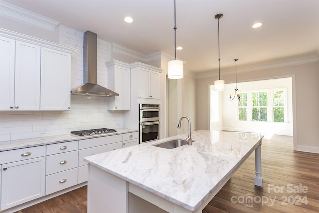 kitchen with wall chimney exhaust hood, a center island with sink, dark wood-type flooring, sink, and white cabinetry