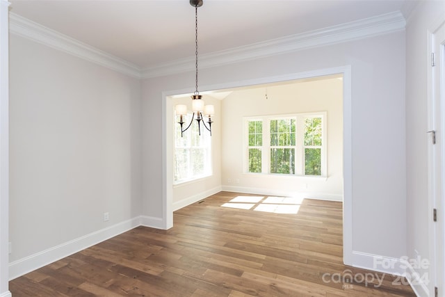 unfurnished dining area featuring crown molding, an inviting chandelier, and hardwood / wood-style flooring