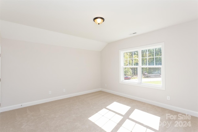 spare room featuring light carpet and lofted ceiling