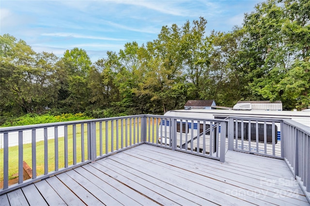 wooden terrace with a storage unit and a lawn