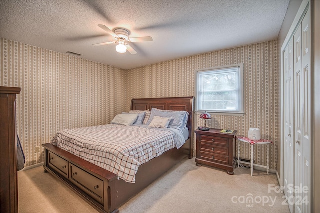 bedroom with ceiling fan, light colored carpet, a textured ceiling, and a closet