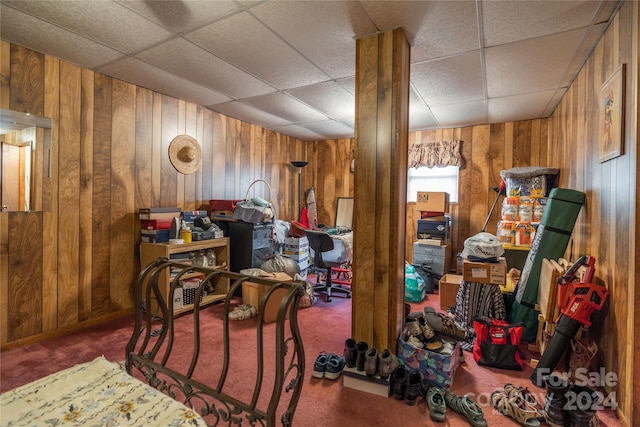 living area featuring wooden walls, a paneled ceiling, and carpet