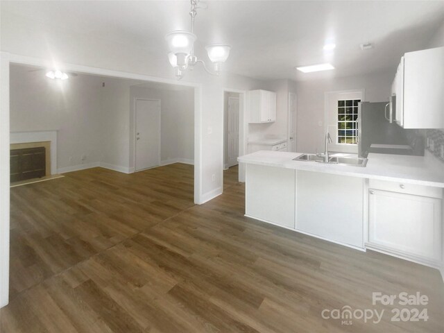 kitchen featuring an inviting chandelier, pendant lighting, dark wood-type flooring, sink, and white cabinets