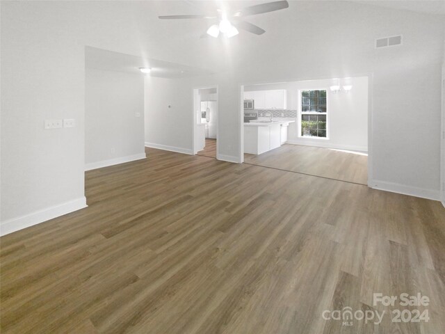 unfurnished living room featuring ceiling fan, wood-type flooring, and vaulted ceiling