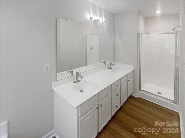 bathroom with hardwood / wood-style floors, a shower with door, and vanity