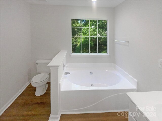 bathroom with a tub to relax in, toilet, hardwood / wood-style flooring, and vanity