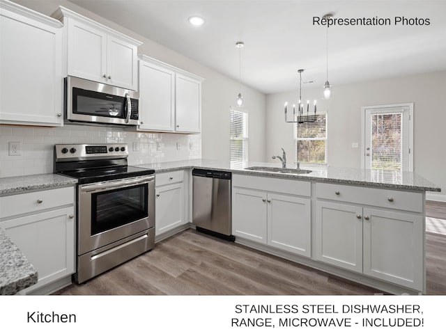 kitchen featuring white cabinetry, stainless steel appliances, sink, hanging light fixtures, and light hardwood / wood-style flooring