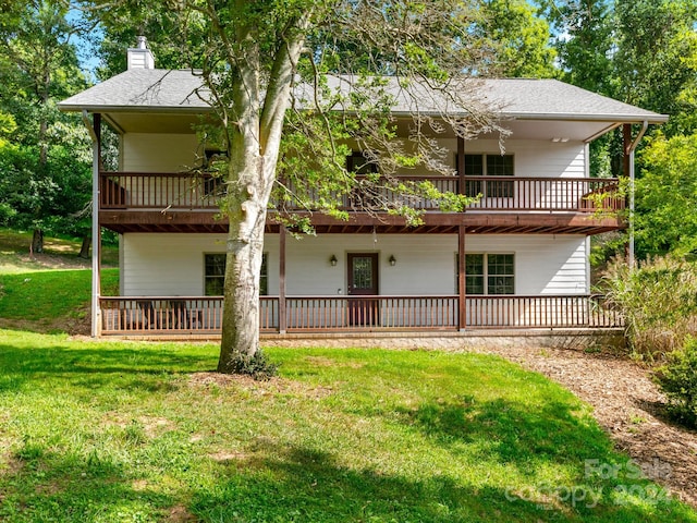 rear view of house featuring a balcony and a lawn