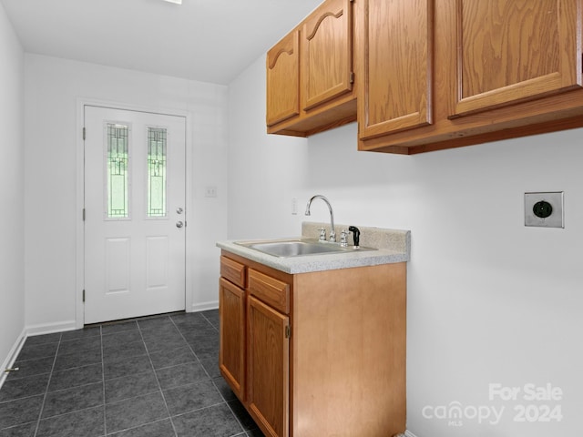 laundry area featuring dark tile patterned flooring, cabinets, and sink