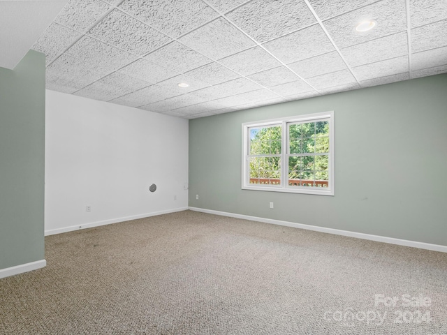 carpeted empty room with a drop ceiling