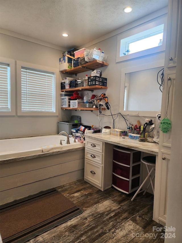 interior space with hardwood / wood-style floors, vanity, a tub to relax in, and a textured ceiling