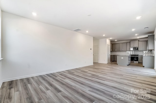 unfurnished living room featuring sink and light hardwood / wood-style floors