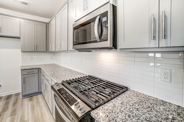 kitchen featuring light stone counters, stainless steel appliances, light hardwood / wood-style flooring, and gray cabinetry