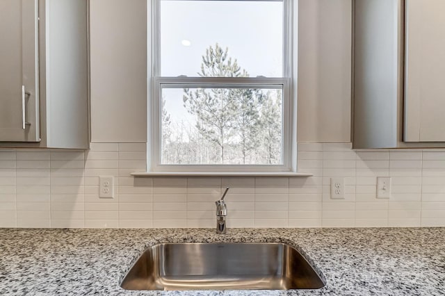 details with tasteful backsplash, sink, and light stone countertops