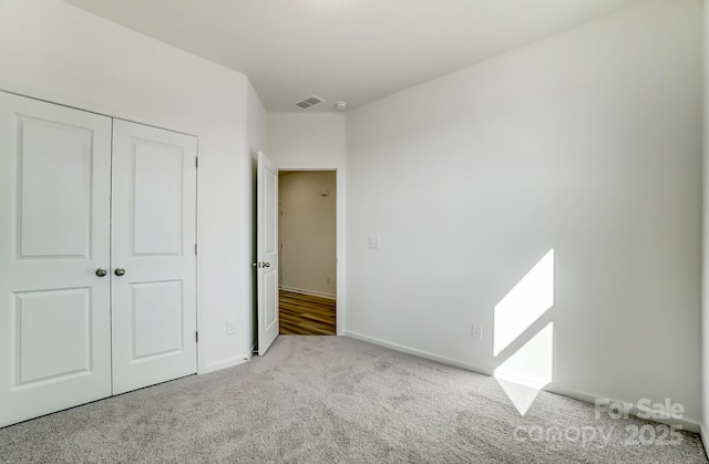 unfurnished bedroom with light carpet and a closet