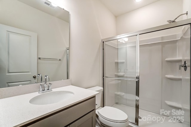 bathroom with an enclosed shower, vanity, and toilet