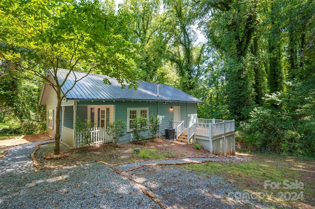 back of property with central AC, a deck, and a porch