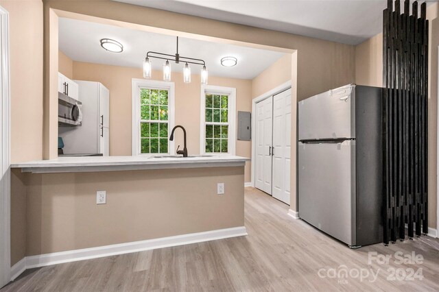 kitchen with light hardwood / wood-style flooring, appliances with stainless steel finishes, hanging light fixtures, and sink