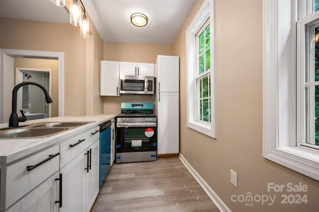 kitchen with a healthy amount of sunlight, stainless steel appliances, sink, and white cabinets