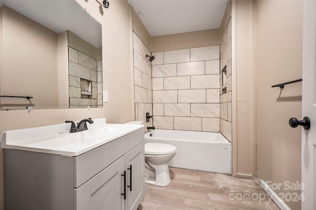 full bathroom with vanity, toilet, wood-type flooring, and tiled shower / bath