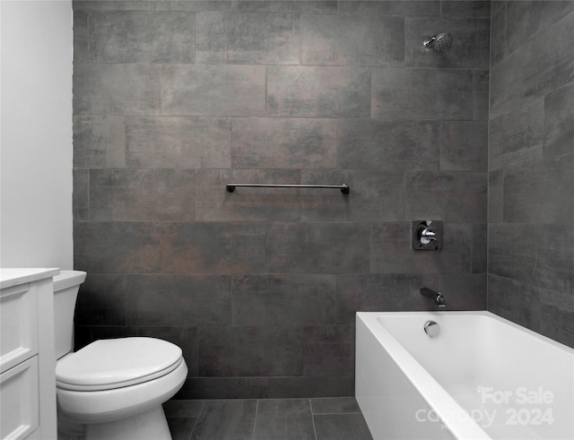 full bathroom with tile patterned flooring, toilet, tile walls, tiled shower / bath combo, and vanity