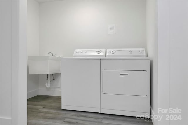 laundry room featuring washing machine and dryer, sink, and light hardwood / wood-style floors