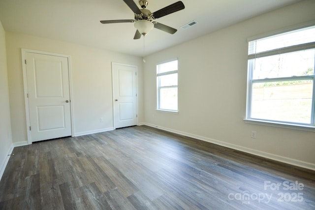 unfurnished bedroom with baseboards, visible vents, a ceiling fan, and dark wood-style floors