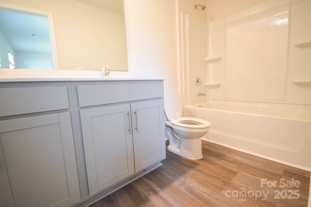 bathroom with bathtub / shower combination, wood finished floors, vanity, and toilet